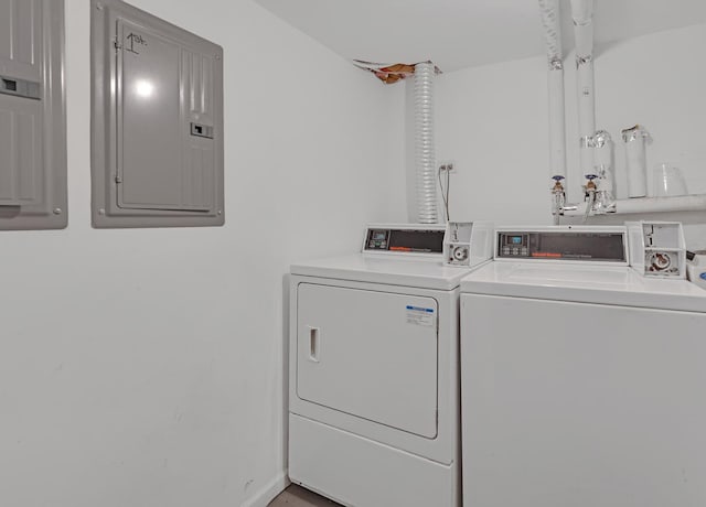 community laundry room with washing machine and clothes dryer, electric panel, and baseboards