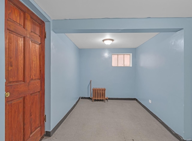 below grade area featuring light floors, radiator, and baseboards