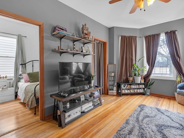 living area featuring wood-type flooring, baseboards, and ceiling fan