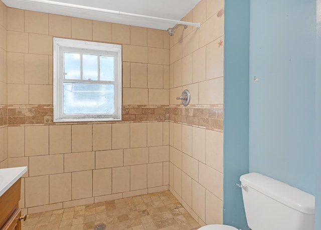 bathroom featuring a tile shower, vanity, and toilet