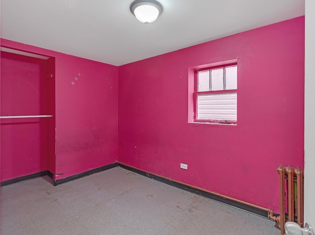 spare room with radiator heating unit, baseboards, and tile patterned floors