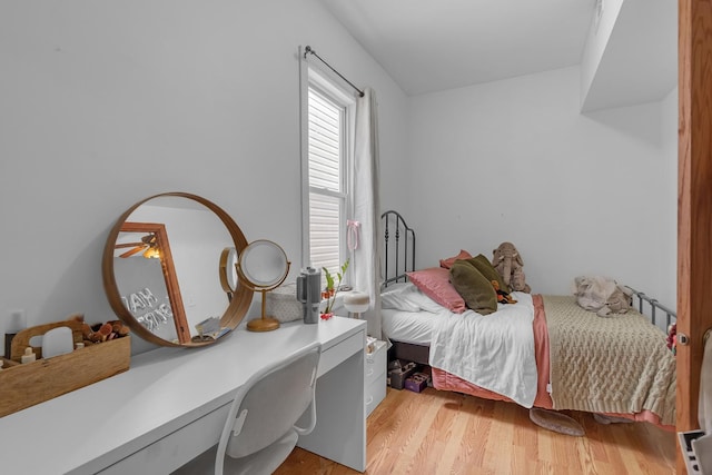 bedroom with built in desk and light wood-style floors