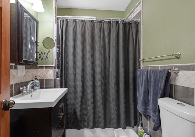 bathroom featuring curtained shower, toilet, a wainscoted wall, vanity, and tile walls