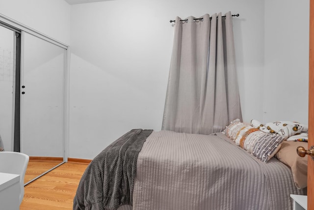 bedroom featuring light wood-style floors, baseboards, and a closet