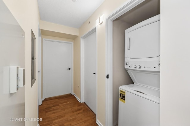 washroom with stacked washer and dryer, laundry area, and wood finished floors