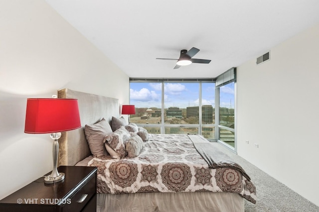 bedroom featuring visible vents, ceiling fan, access to exterior, expansive windows, and a city view