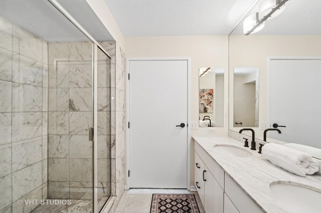 bathroom featuring double vanity, a stall shower, a textured ceiling, and a sink