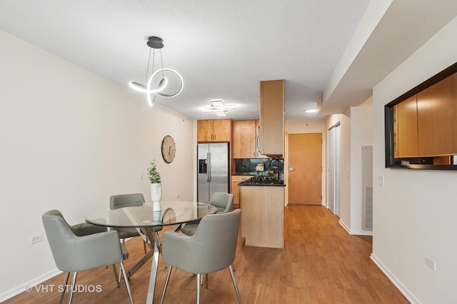 dining room with light wood-type flooring, visible vents, and baseboards