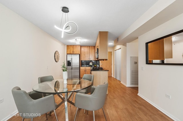 dining room featuring light wood-type flooring, visible vents, and baseboards