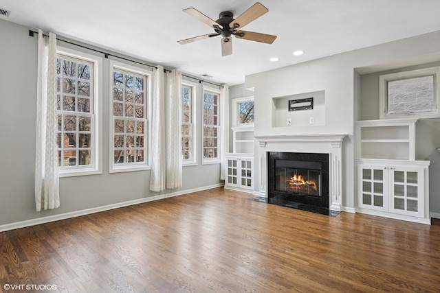 unfurnished living room featuring visible vents, baseboards, a fireplace with flush hearth, recessed lighting, and wood finished floors