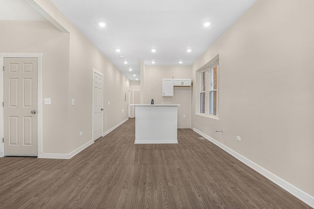 unfurnished living room with recessed lighting, dark wood finished floors, and baseboards