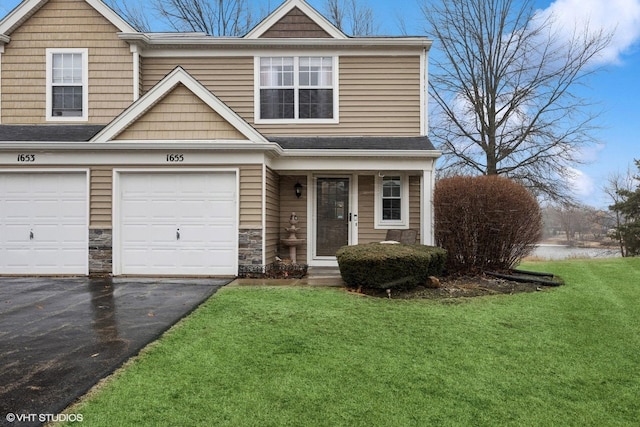 view of front of property featuring a garage, driveway, a front lawn, and stone siding