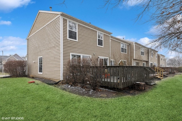 rear view of house featuring a lawn and a deck