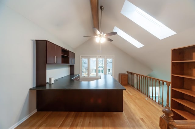 unfurnished office featuring light wood-style floors, vaulted ceiling with skylight, baseboards, and a ceiling fan