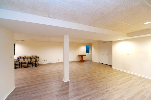 finished basement with a paneled ceiling, recessed lighting, baseboards, and wood finished floors