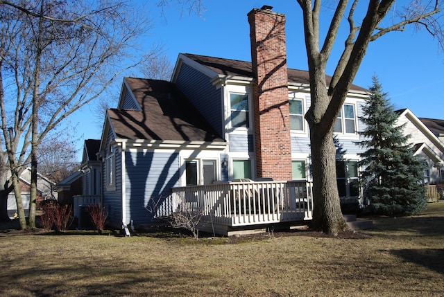 view of property exterior with a lawn, a chimney, and a wooden deck