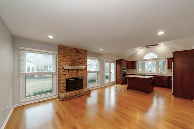 kitchen featuring open floor plan, light wood-style floors, a fireplace, and a center island