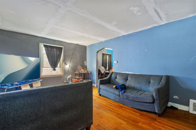 living area featuring arched walkways, wood finished floors, and baseboards