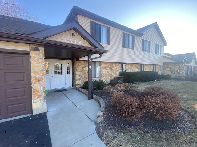 view of exterior entry featuring stone siding and an attached garage