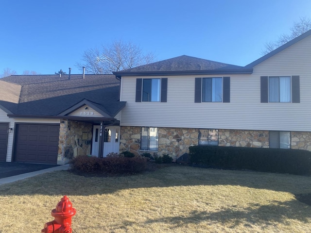 view of front of property featuring an attached garage, stone siding, a shingled roof, and a front yard