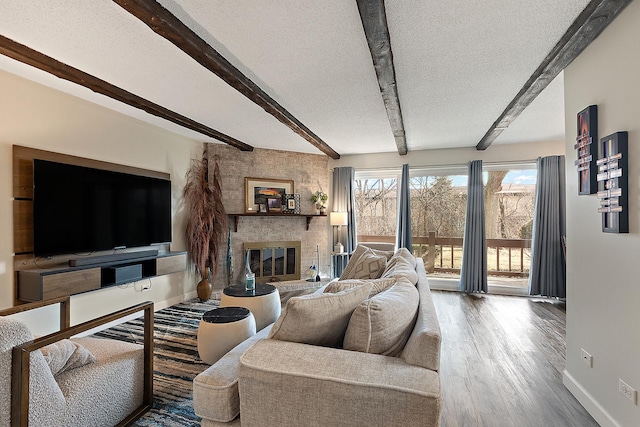 living room featuring a textured ceiling, a fireplace, wood finished floors, baseboards, and beamed ceiling