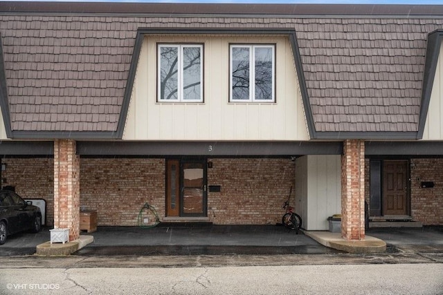 view of front facade with brick siding and mansard roof