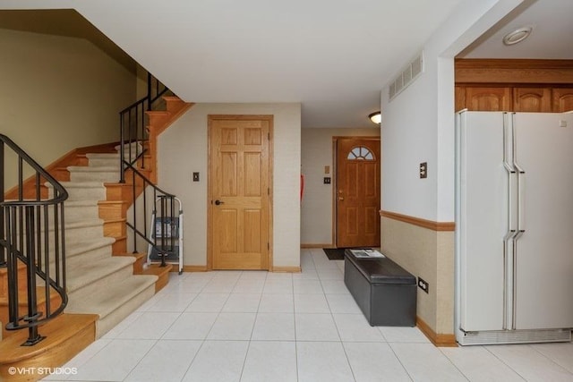 entryway featuring stairs, light tile patterned floors, visible vents, and baseboards