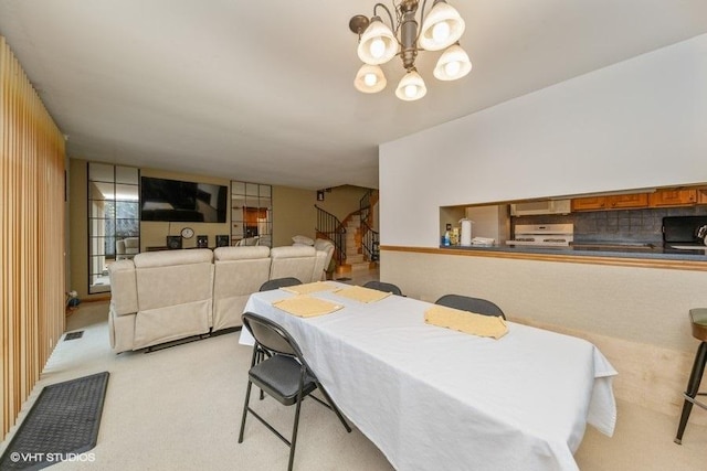 dining space with light carpet, stairs, and a notable chandelier