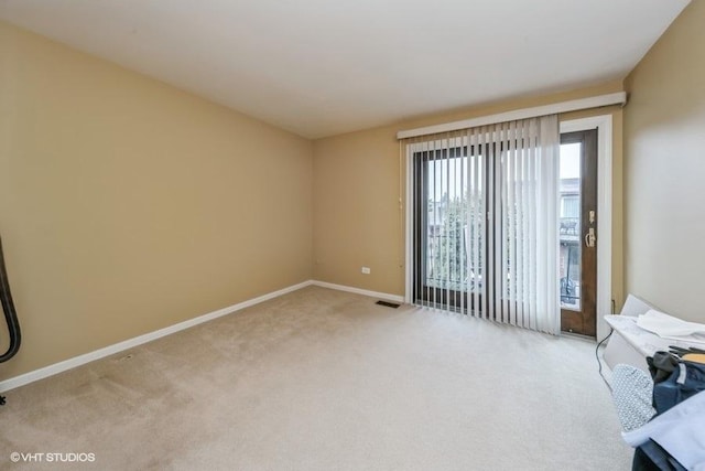 empty room with carpet floors, visible vents, and baseboards