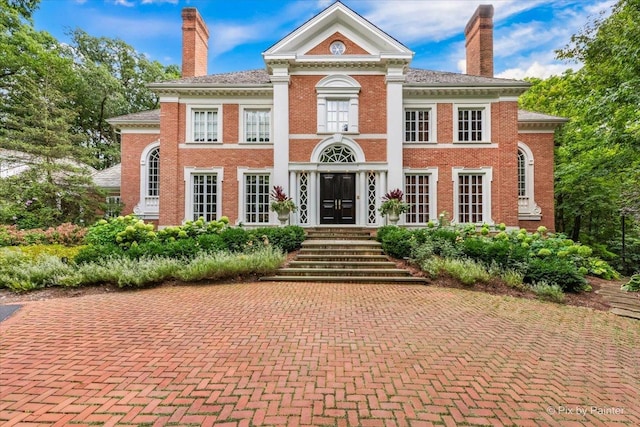 greek revival house with brick siding and a chimney