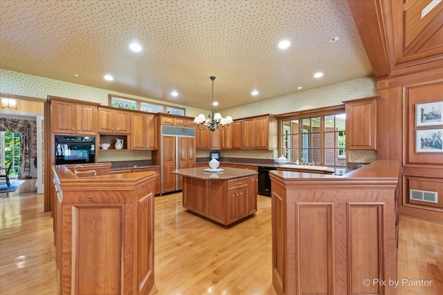 kitchen featuring black appliances, a kitchen island, visible vents, and wallpapered walls