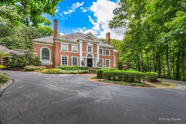 neoclassical home featuring brick siding and a chimney