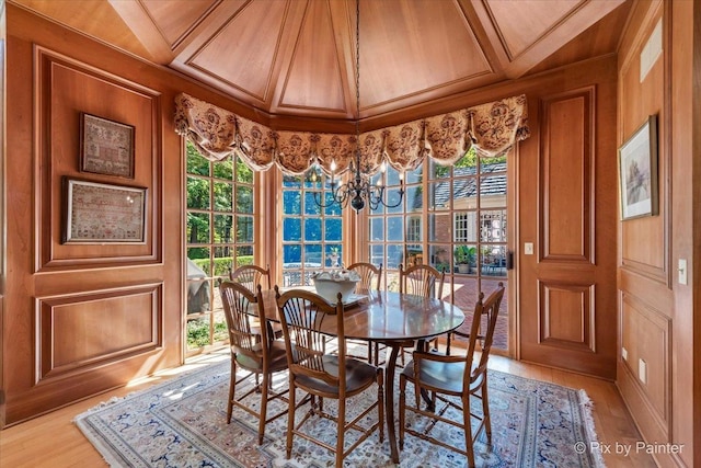 dining space with a chandelier, wooden walls, and wood finished floors