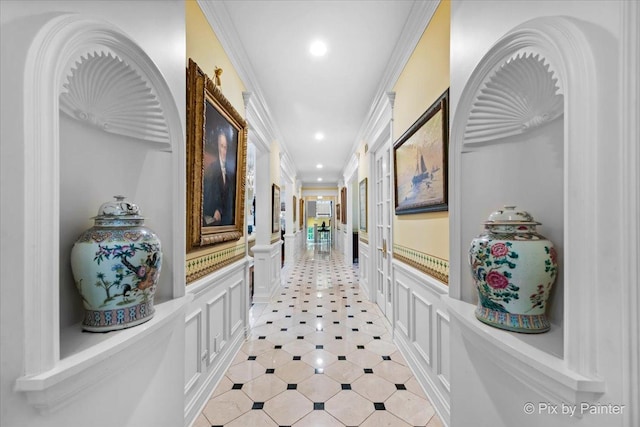 hallway featuring crown molding, recessed lighting, wainscoting, and a decorative wall