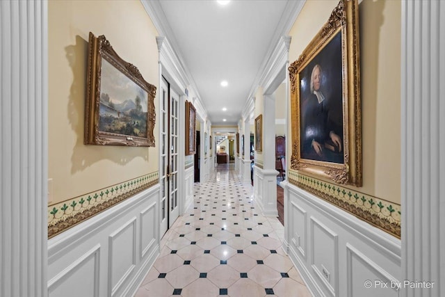 hall with crown molding, recessed lighting, wainscoting, and a decorative wall