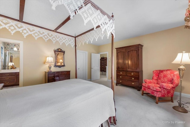 bedroom with connected bathroom and light colored carpet