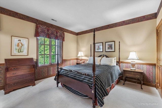 bedroom featuring a wainscoted wall, carpet, visible vents, and wallpapered walls