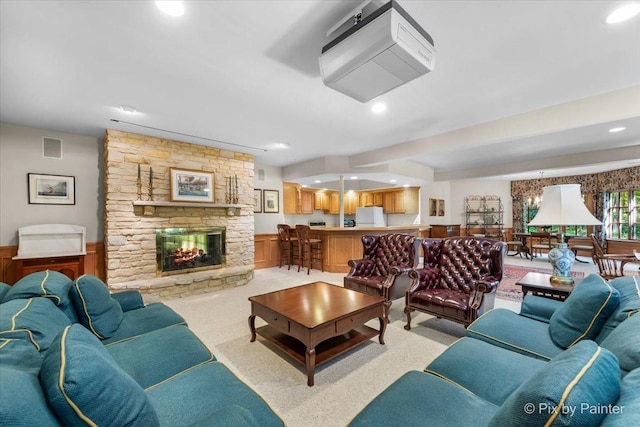 living room featuring recessed lighting, a wainscoted wall, light colored carpet, a fireplace, and visible vents