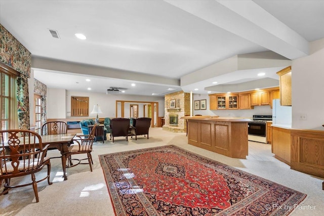 kitchen featuring a large fireplace, glass insert cabinets, stove, open floor plan, and light countertops