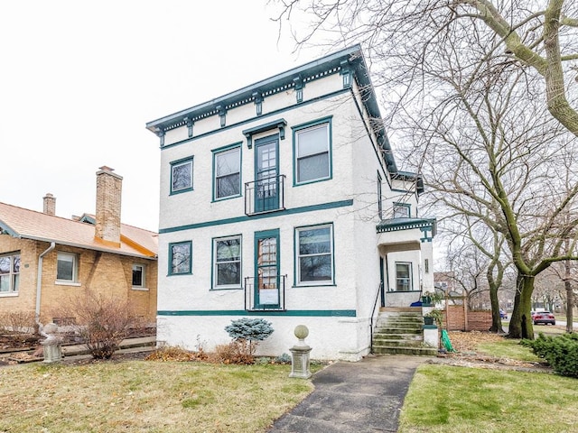 italianate home featuring a front yard and stucco siding