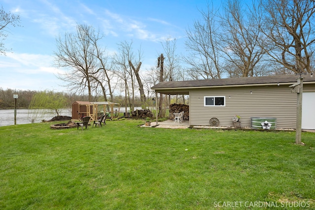 view of yard with a shed, a water view, an outbuilding, and a patio