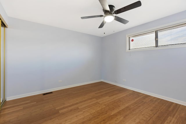 spare room with a ceiling fan, wood finished floors, visible vents, and baseboards