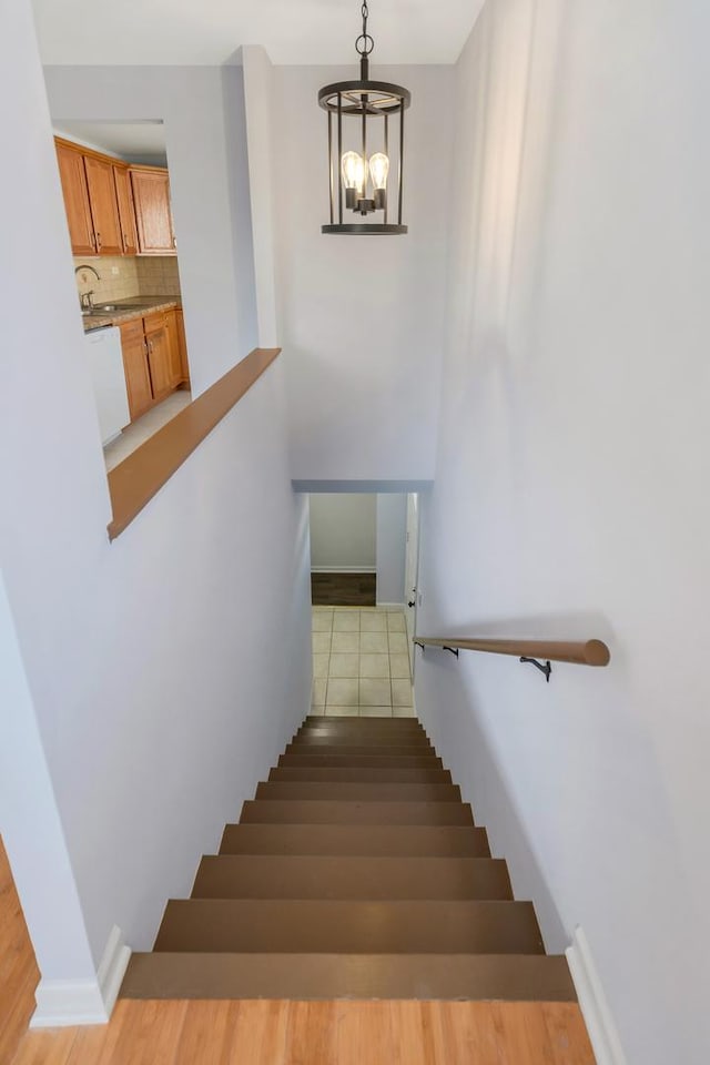 stairs with baseboards and an inviting chandelier