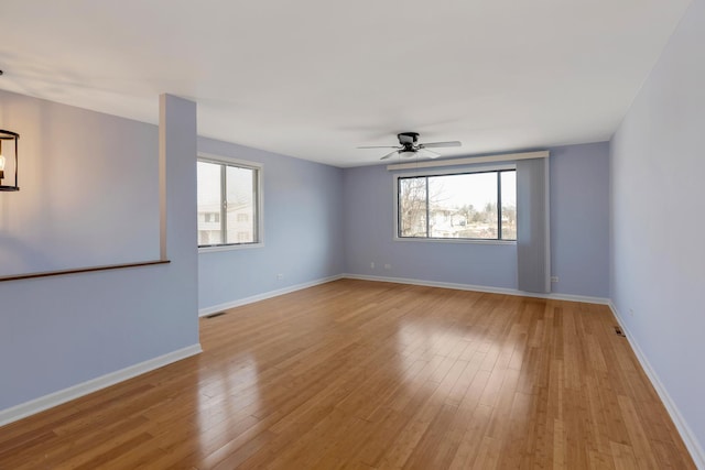 empty room with light wood-style floors, visible vents, baseboards, and a wealth of natural light