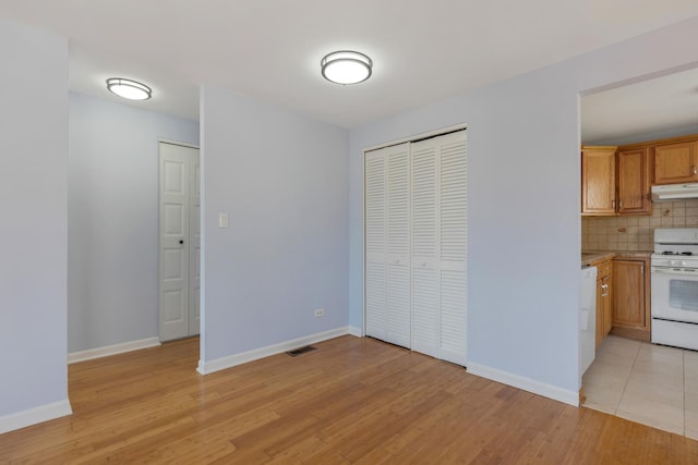 interior space with light wood-type flooring, visible vents, and baseboards