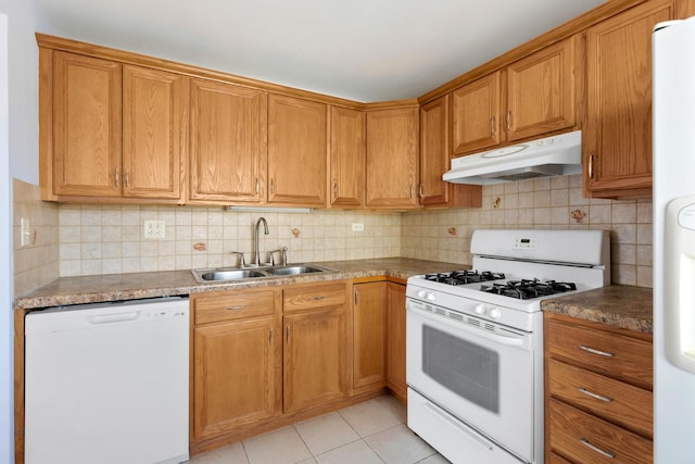 kitchen with white appliances, light tile patterned floors, decorative backsplash, under cabinet range hood, and a sink