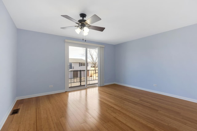 empty room with a ceiling fan, visible vents, baseboards, and wood finished floors