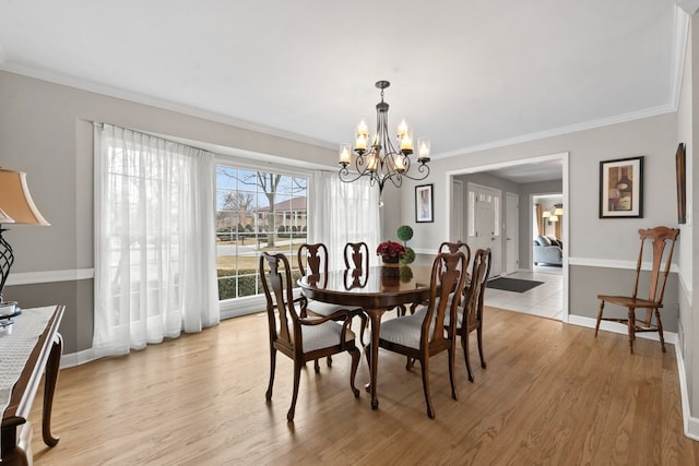 dining space with light wood-type flooring, crown molding, baseboards, and an inviting chandelier