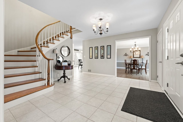 foyer entrance featuring tile patterned floors, visible vents, a chandelier, baseboards, and stairs