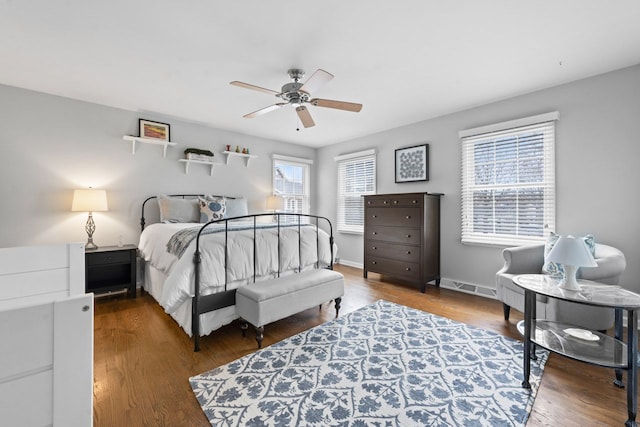 bedroom with a ceiling fan, visible vents, baseboards, and wood finished floors